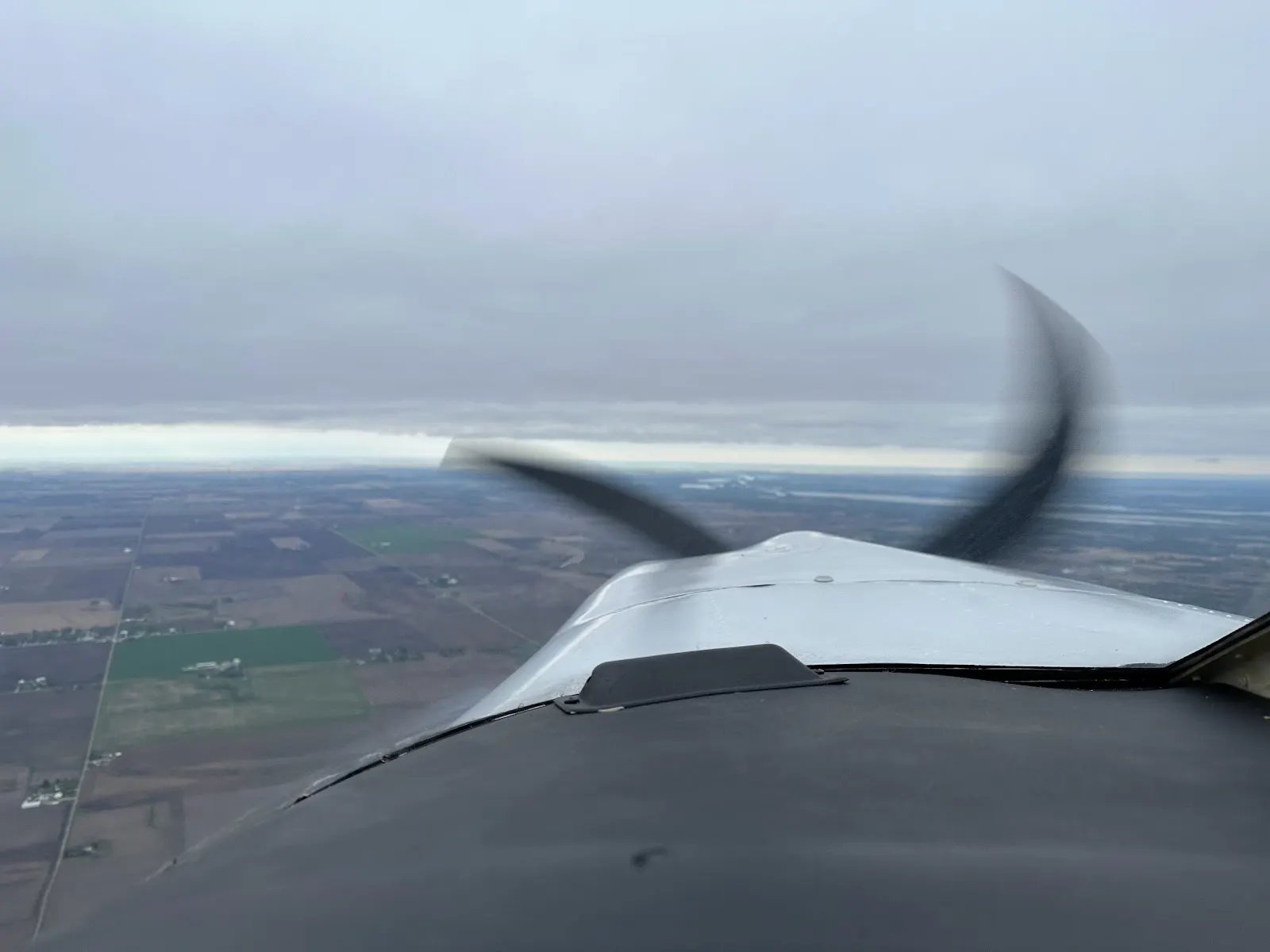 Cruising over farmland, propeller spinning